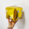 A golden foil balloon shaped like a dice is decorated with white polka dots, held by a hand.