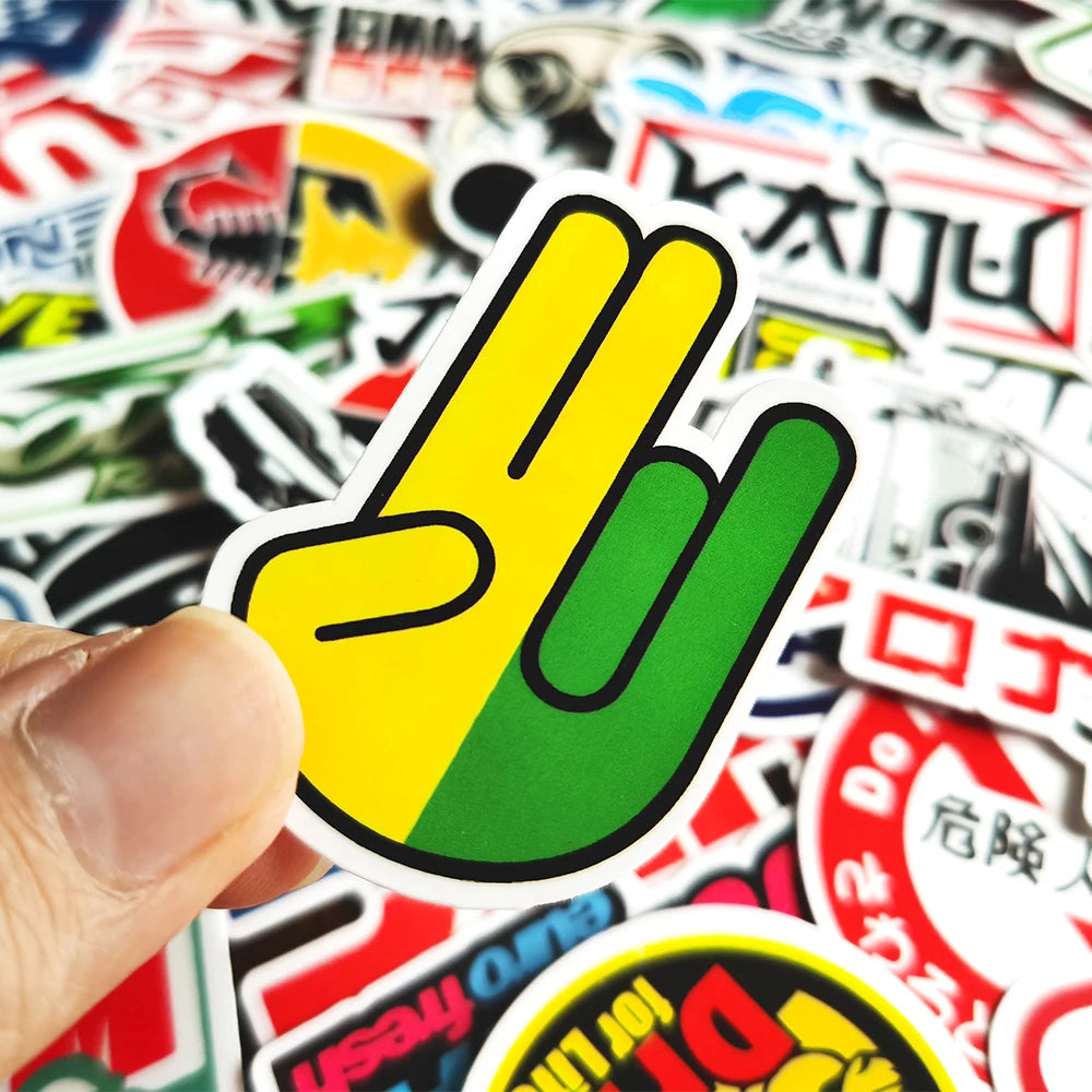 A hand holds a yellow and green JDM style vinyl decal sticker on a white background.