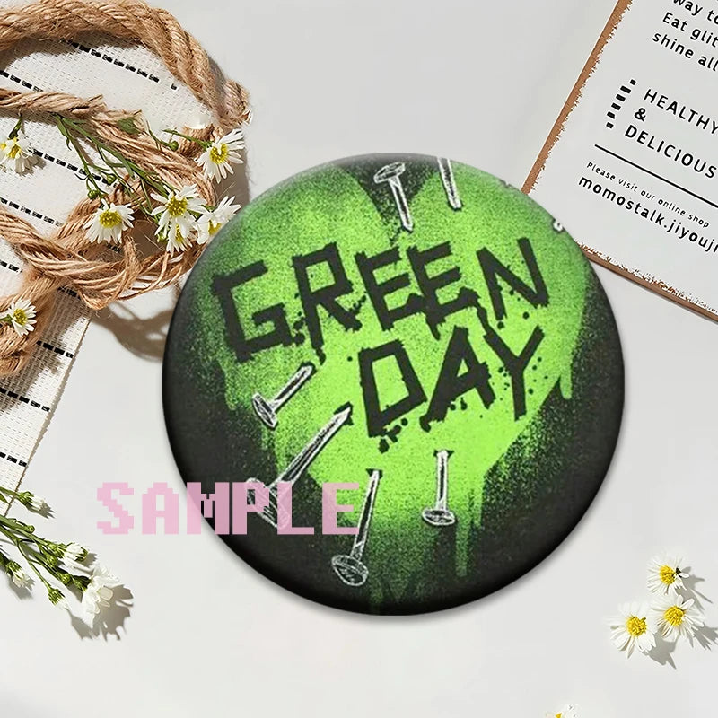 A set of green button pins with the text GREEN DAY printed in a distressed style on a dark background.