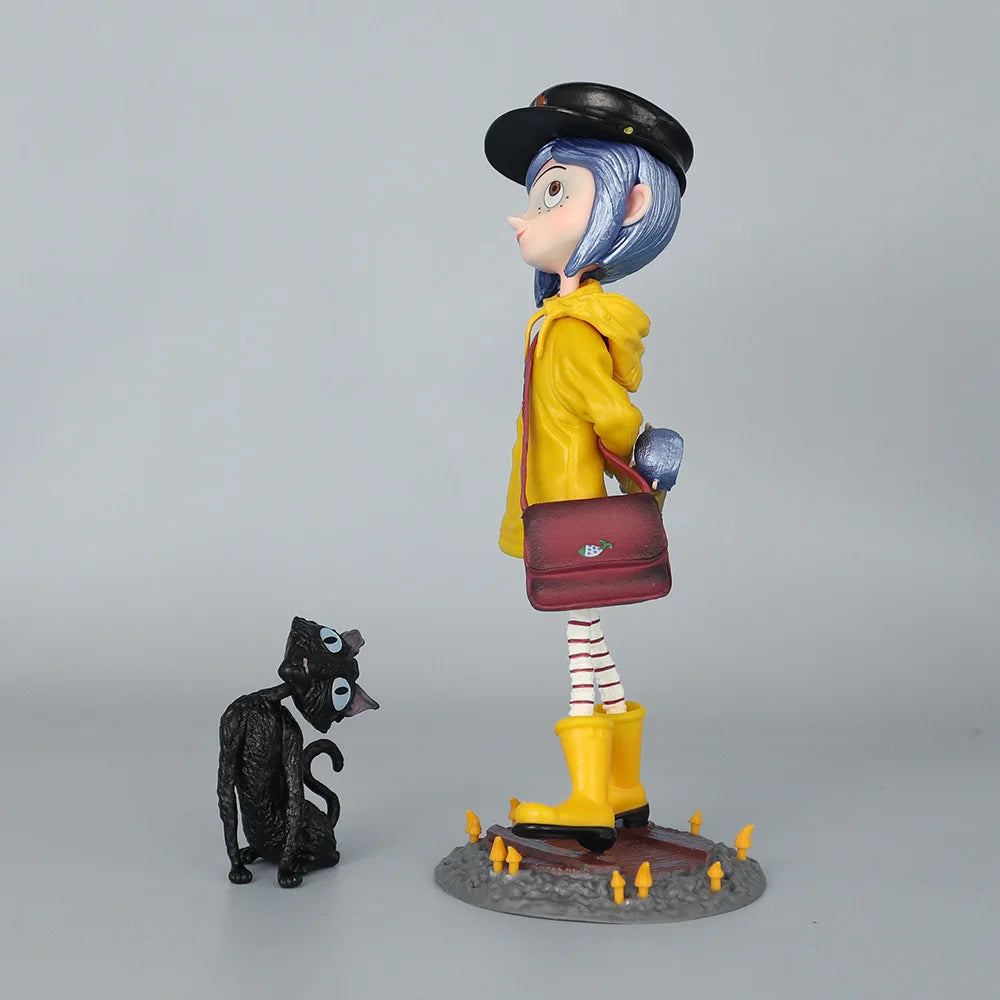 A figurine of a blue-haired girl in a yellow coat and black hat standing next to a small black cat.