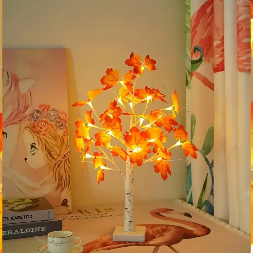 An LED maple leaf table lamp with a warm glow displayed on a wooden surface.