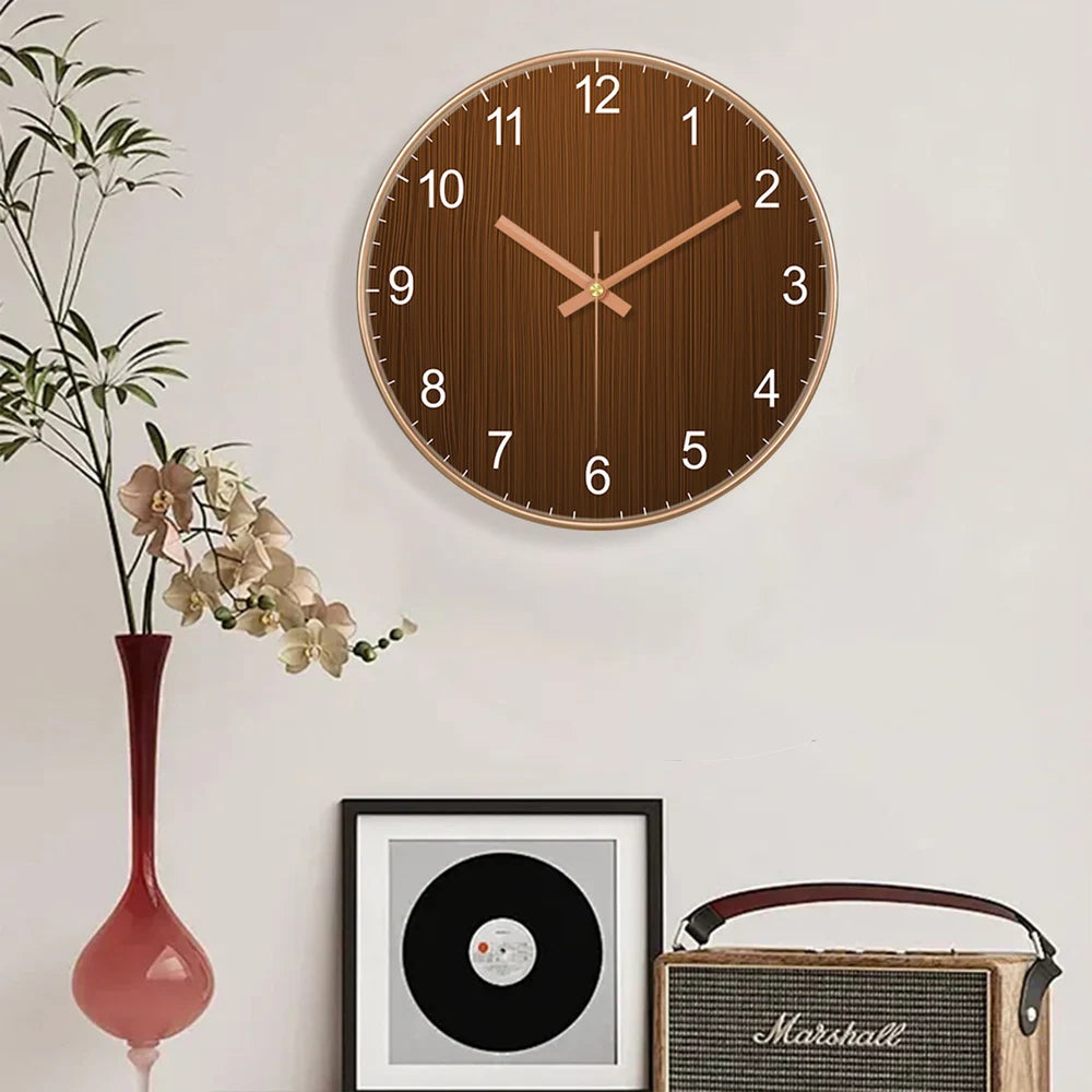 Minimalistische, runde Holz-Wanduhr in Roségold auf weißer Wand neben einer Marshall-Gitarrentasche.
