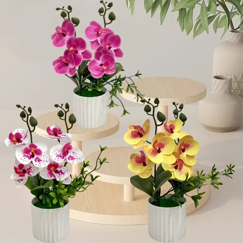 Artificial Phalaenopsis orchids in pink and yellow bloom displayed in white pots on a wooden stand.