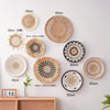A collection of round boho straw wall hangings with varying diameters and woven tassels displayed on a white wall.
