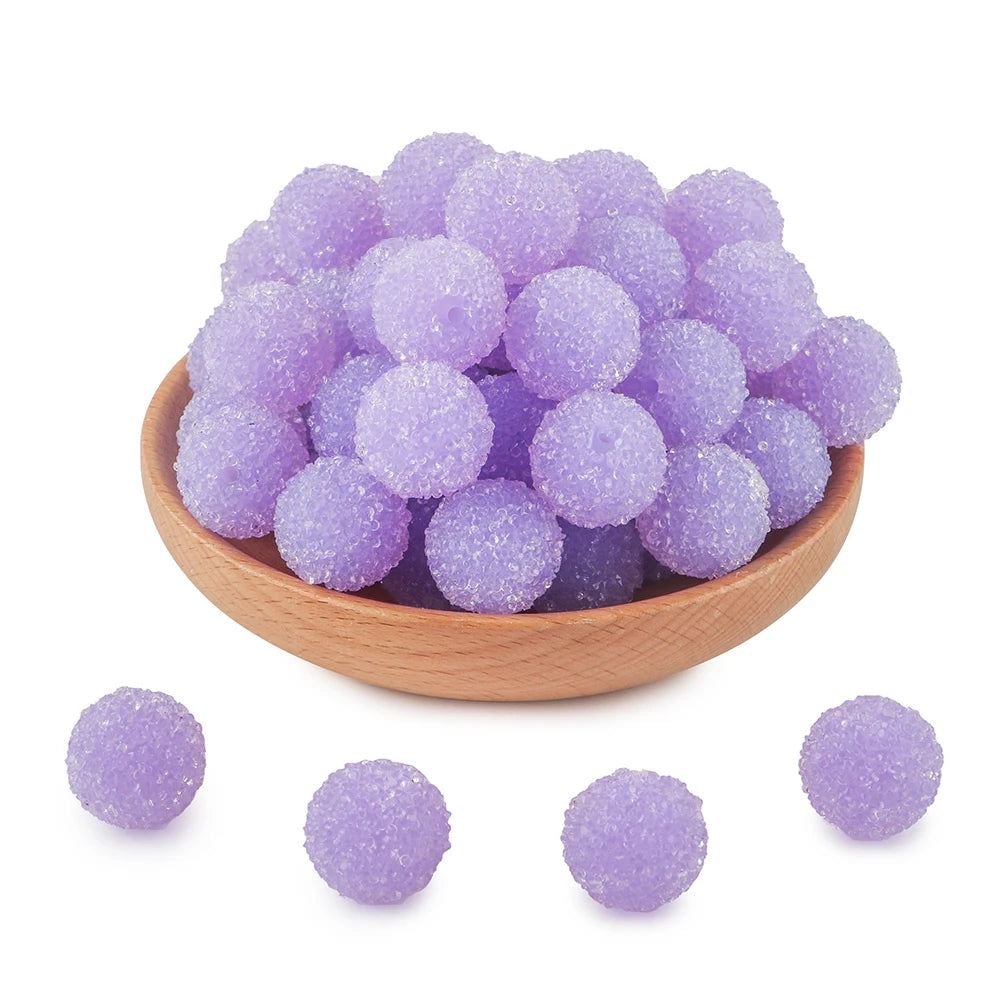 A wooden bowl filled with a pile of small, purple, glittery resin beads for jewelry making.