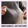 A hand sprays an anti-static fabric spray onto a gray knitted sweater to smooth wrinkles.