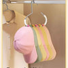 A round multi-purpose closet hook is hanging on a metal bar, displaying eight colorful hats.