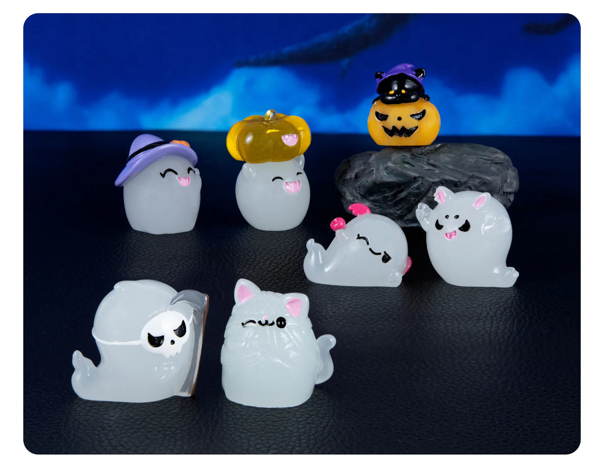 A set of seven cute luminous ghost resin ornaments in various colors and shapes displayed on a dark surface.