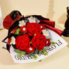 A bouquet of handcrafted red crochet roses wrapped in dark red paper and presented on a white card.