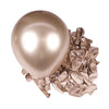 A single, large, spherical chrome metallic latex balloon resting on a pile of crumpled metallic foil balloons.