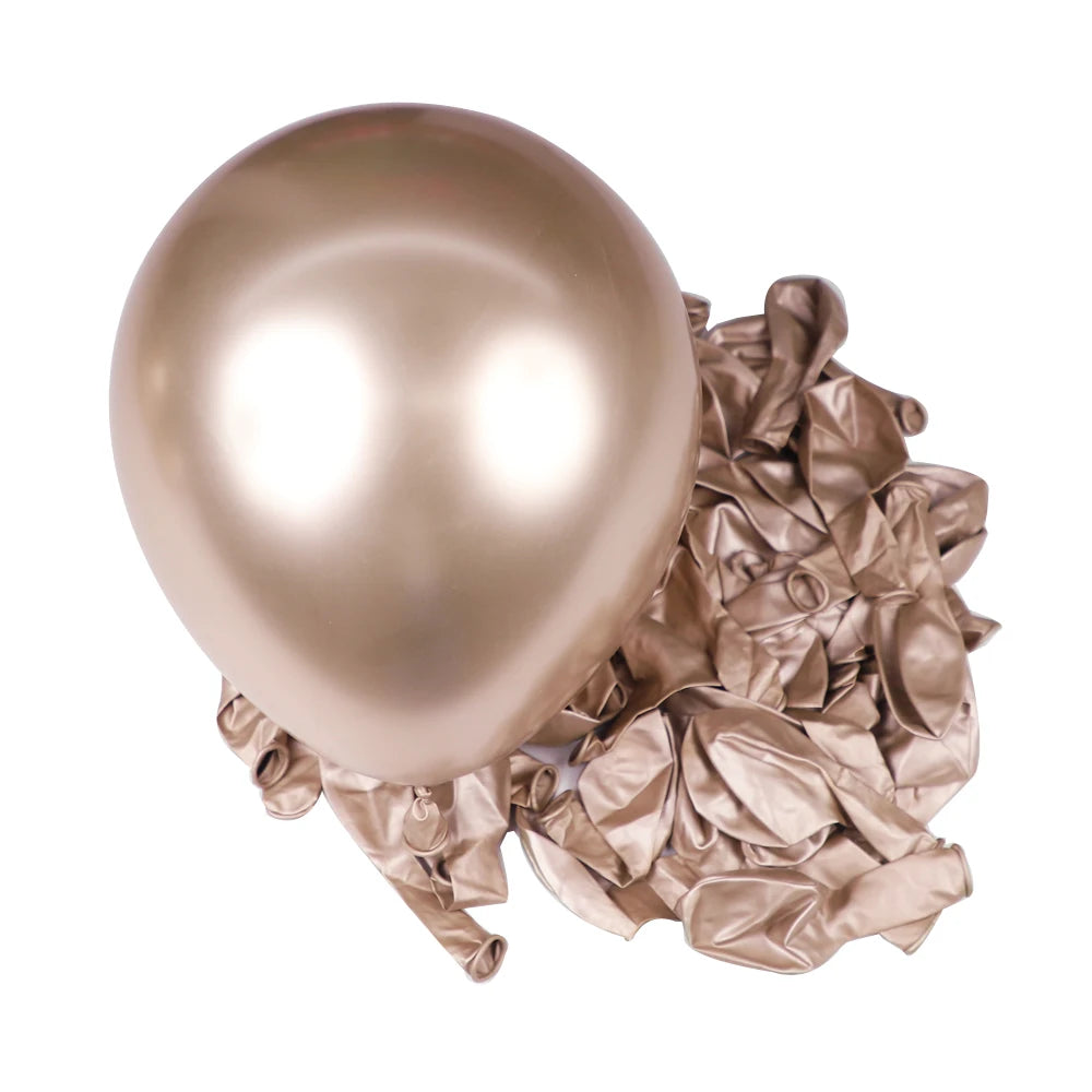 A single, large, spherical chrome metallic latex balloon resting on a pile of crumpled metallic foil balloons.