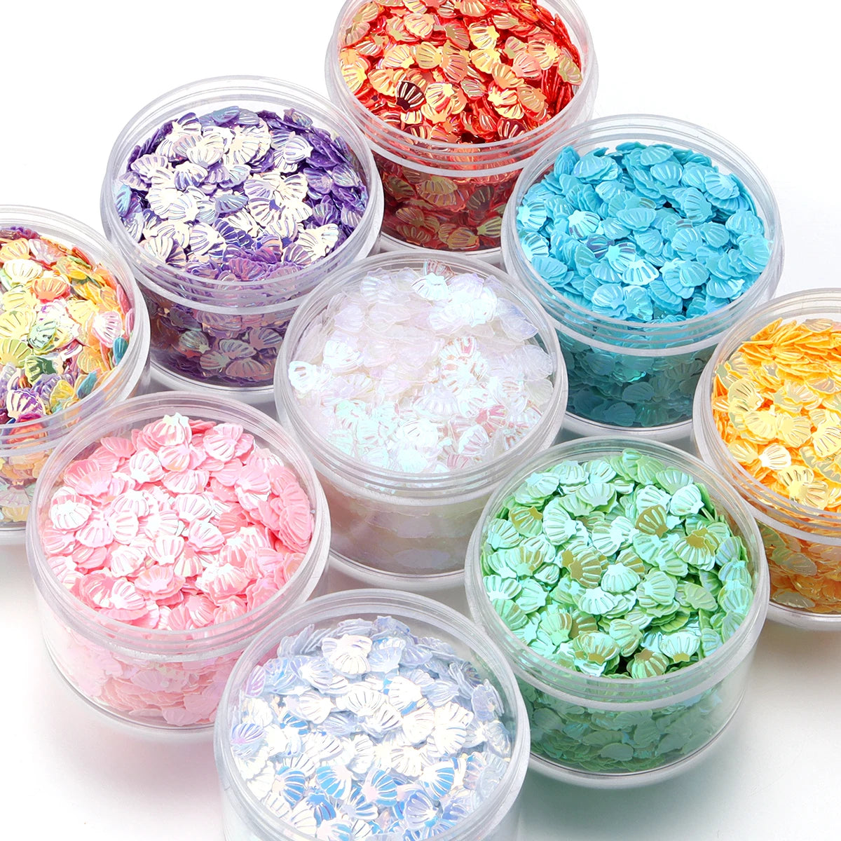 A collection of colorful sea shell PVC sequins in various shades and sizes for nail art and craft decoration.