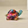 Bunte Kristall-Schildkrötenfigur mit irisierenden Schuppen und strukturiertem Körper auf heller Oberfläche.