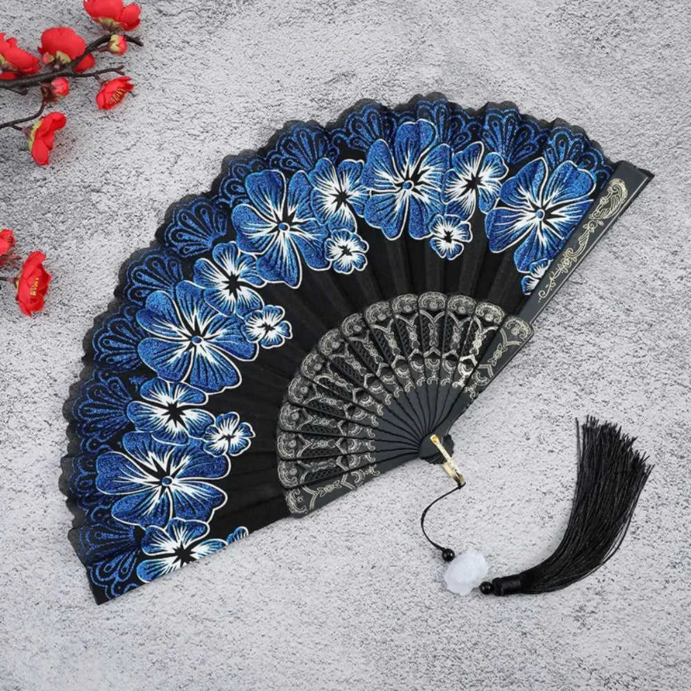 A dark blue and white floral patterned antique folding fan displayed on a gray surface.