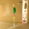 A hanging crystal decor featuring a green natural agate stone and gold accents, catching light on a surface.
