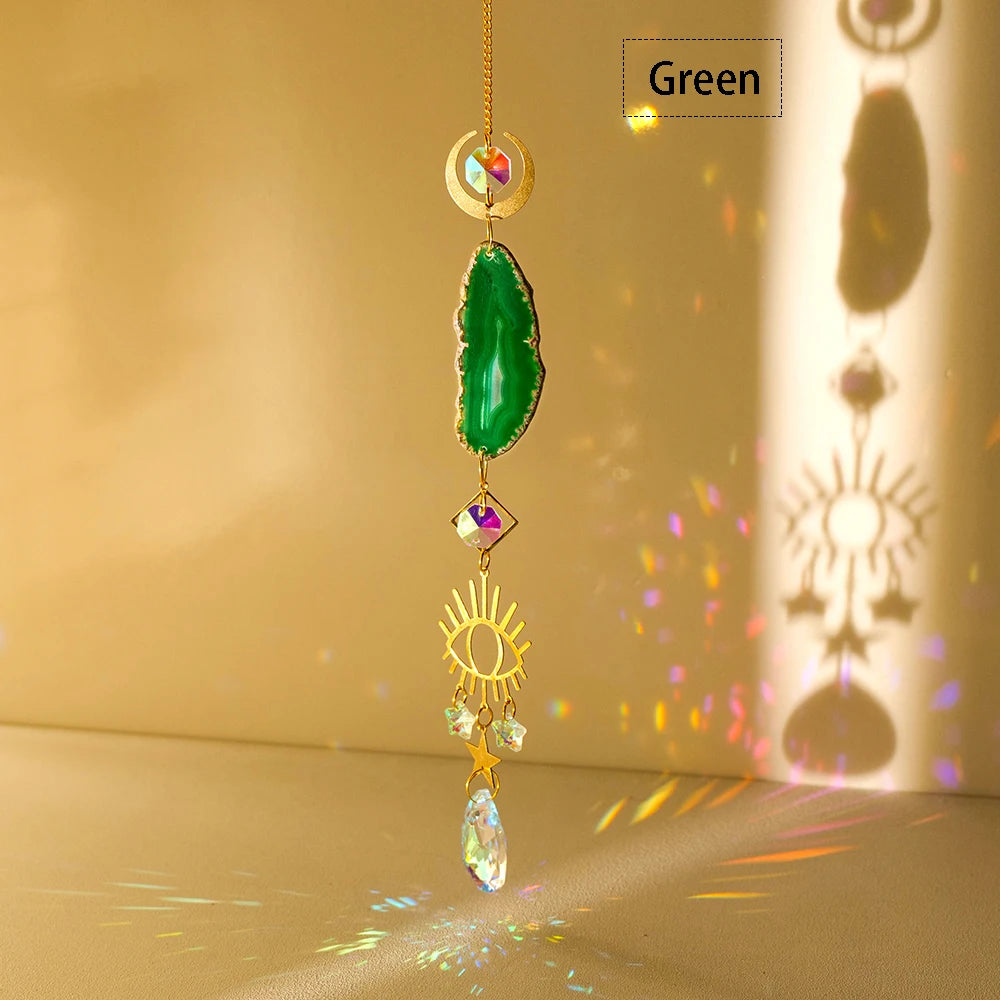 A hanging crystal decor featuring a green natural agate stone and gold accents, catching light on a surface.