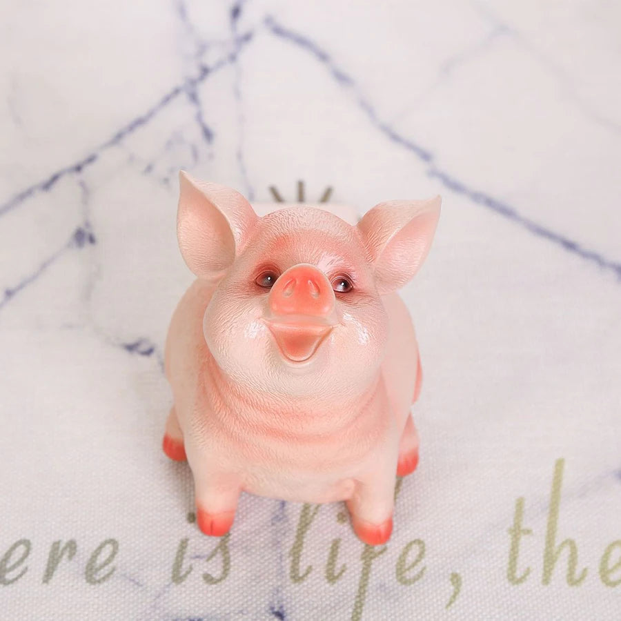 A cute pink resin piggy bank with large ears sitting on a white surface.