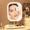 An LED touch-sensitive vanity mirror displays a woman's face with white lighting and is placed on a light surface.