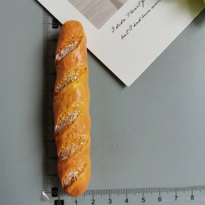 A golden loaf of bread is positioned next to a ruler and a piece of paper.