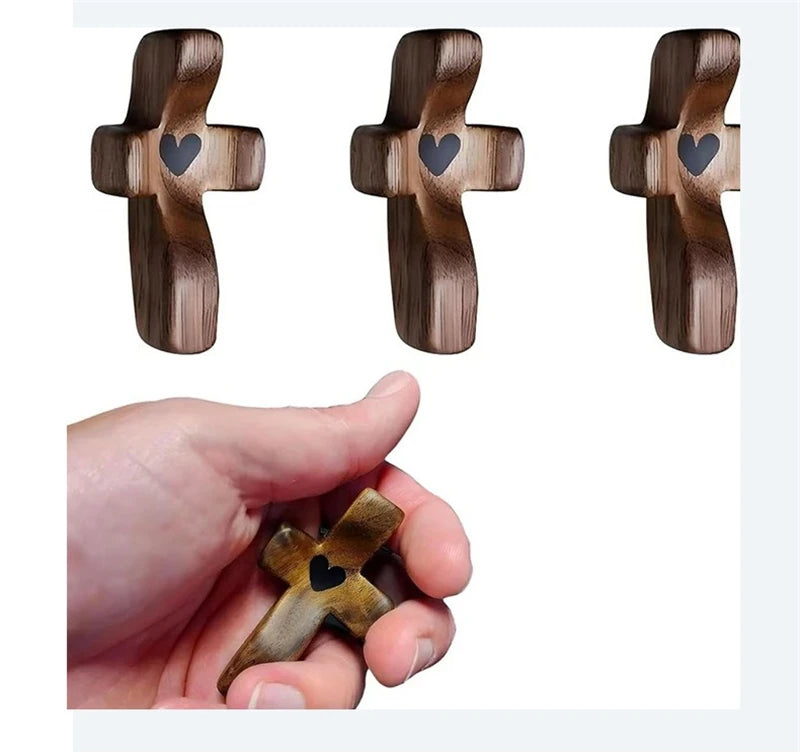 Three wooden crosses with epoxy hearts shown next to a hand for scale