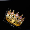 A gold-toned crystal rhinestone crown featuring pink and clear gemstones, shown against a black background.