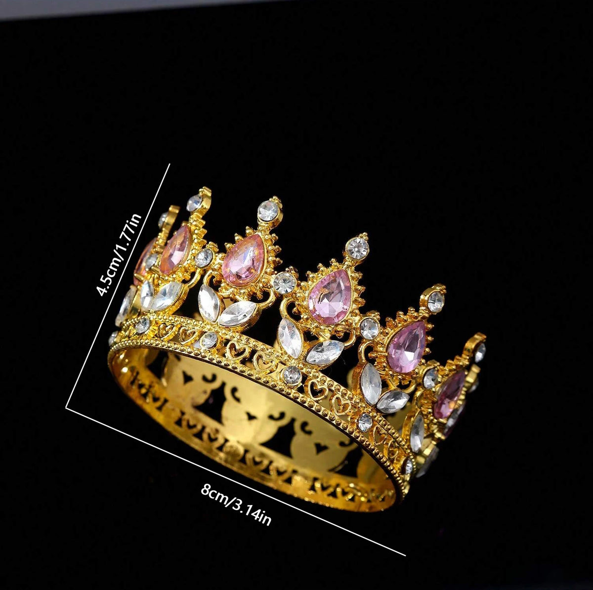 A gold-toned crystal rhinestone crown featuring pink and clear gemstones, shown against a black background.
