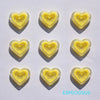 A set of yellow heart-shaped acrylic charms against a white background.