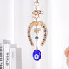 Gold horseshoe wall hanging with an elephant charm and a blue eye pendant