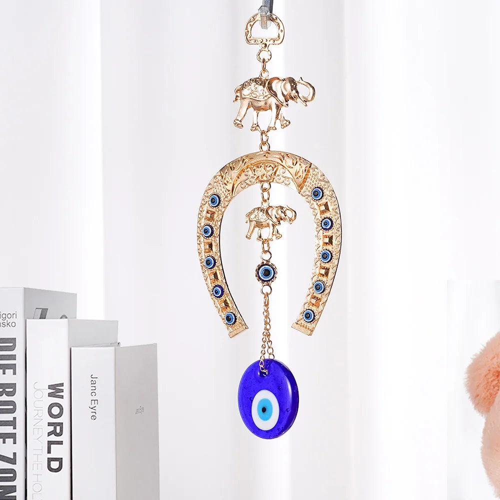 Gold horseshoe wall hanging with an elephant charm and a blue eye pendant