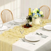 A white table set featuring a sage green gauze table runner, white plates, silverware, and a glass of sparkling wine with a f