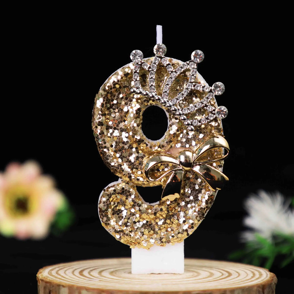 Gold glitter number cake topper featuring a large number with a rhinestone bow and candle.