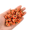 A hand holds a cluster of 20 orange resin pumpkin charms for fall decor.
