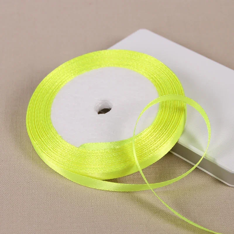 A spool of bright yellow satin ribbon is shown on a white background.