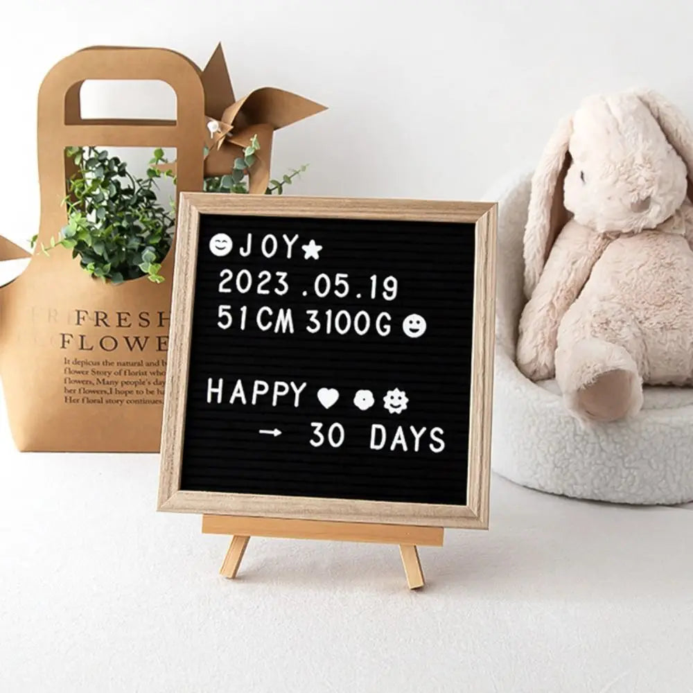 A wooden letter message board displaying a birth date, weight, and a countdown for a baby.