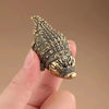 A detailed antique copper alligator desk decor figurine is held in a hand.