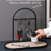 A black wrought iron key holder rack displaying various keys and a watch on a desk.