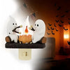 A white ghost figurine is shown next to a glowing orange bonfire in a night light display.