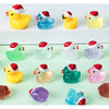 A collection of glow-in-the-dark duck figurines with Santa hats in various colors on a light green surface.