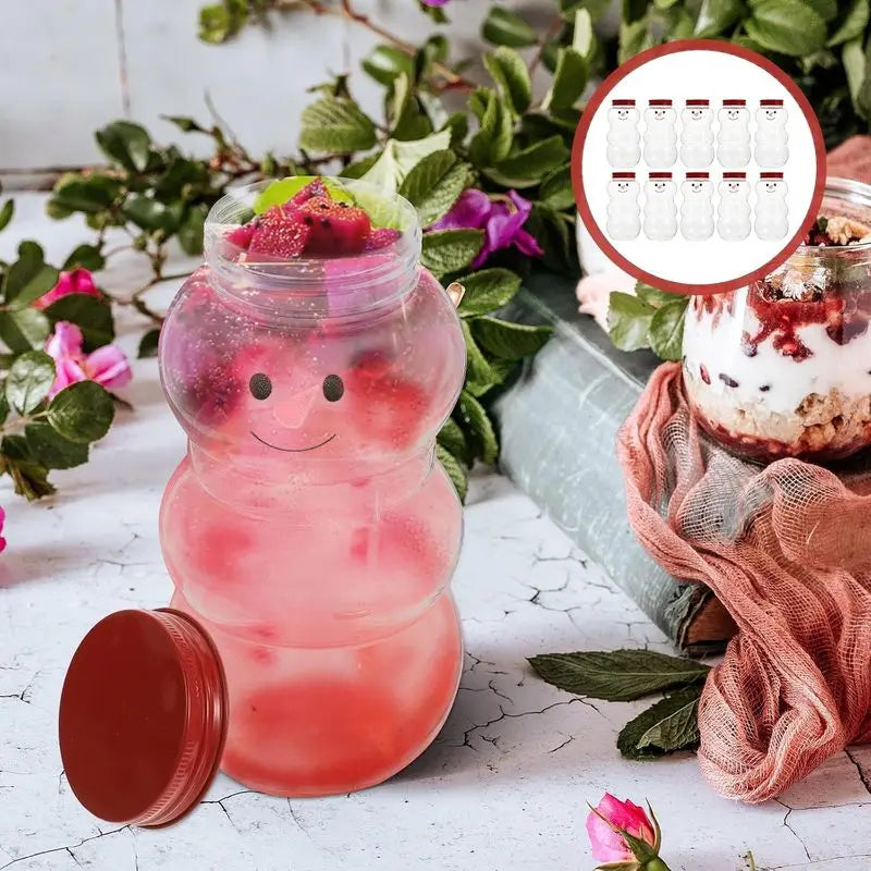A set of six festive snowman candy jars with lids filled with pink liquid and fruit, displayed on a white surface.