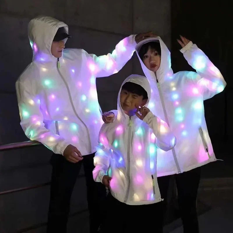 Two people wearing white light-up neon costume jackets and pants, illuminated by colorful LED lights.