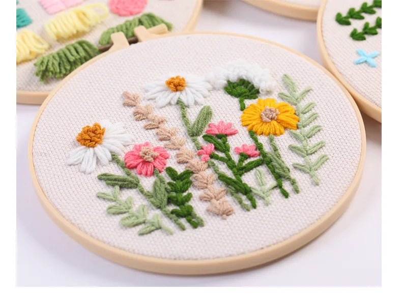 Punch needle embroidery kit featuring a floral design with white, yellow, and pink flowers on natural cloth.