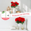 A bouquet of vibrant red artificial silk roses in a white vase displayed on a light-colored surface.