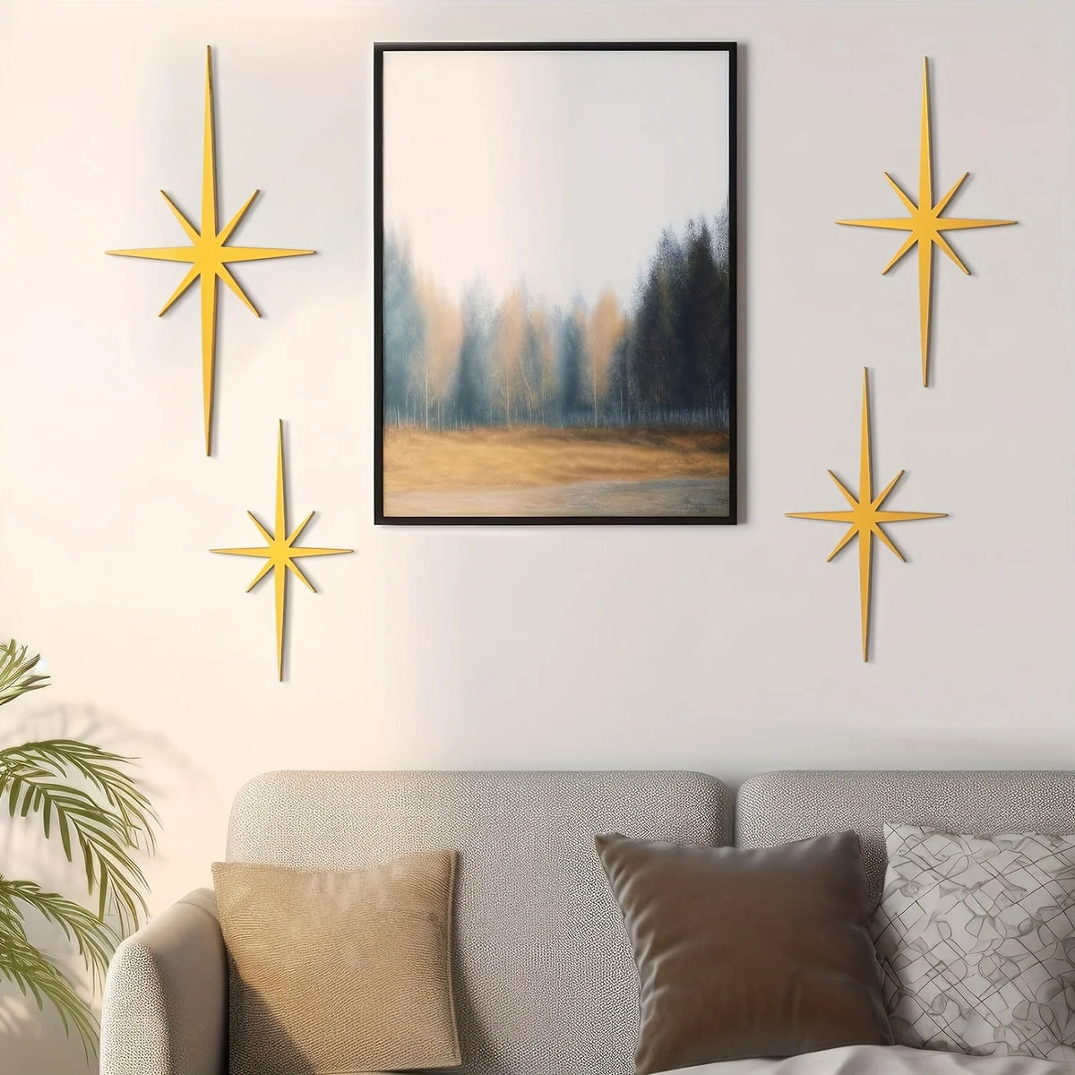 A set of four gold metal star wall art pieces displayed on a light gray wall above a sofa.