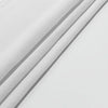 A close-up of white fabric or tapestry with subtle vertical lines, folded and draped.