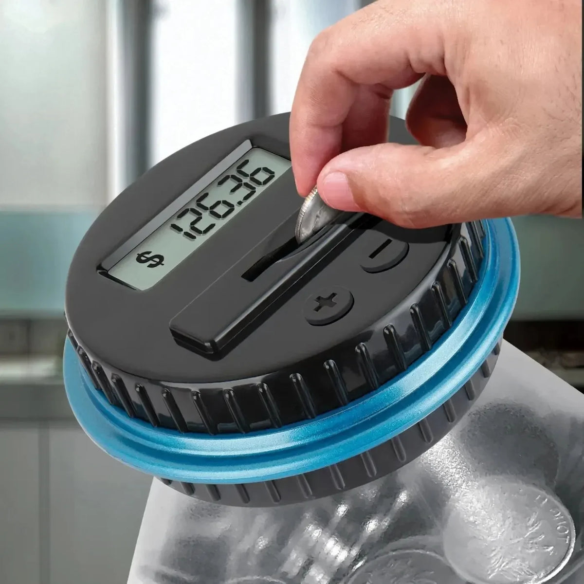 A hand is using a digital coin counting piggy bank with an LCD display to count coins.