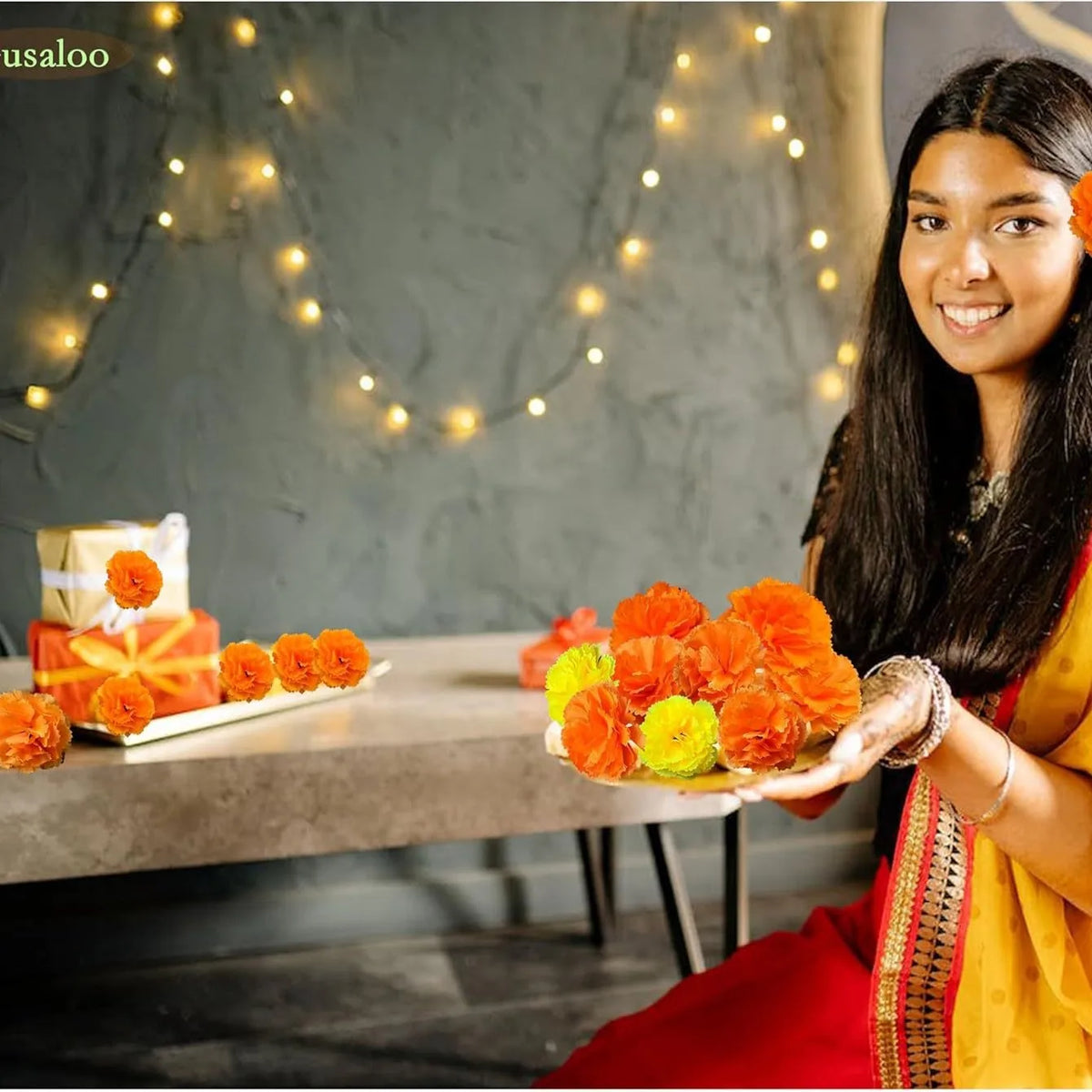 A smiling woman holds a bouquet of orange and yellow marigold flowers against a dark gray background.