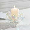 A clear crystal lotus flower holder with a white candle and flame on a white surface.