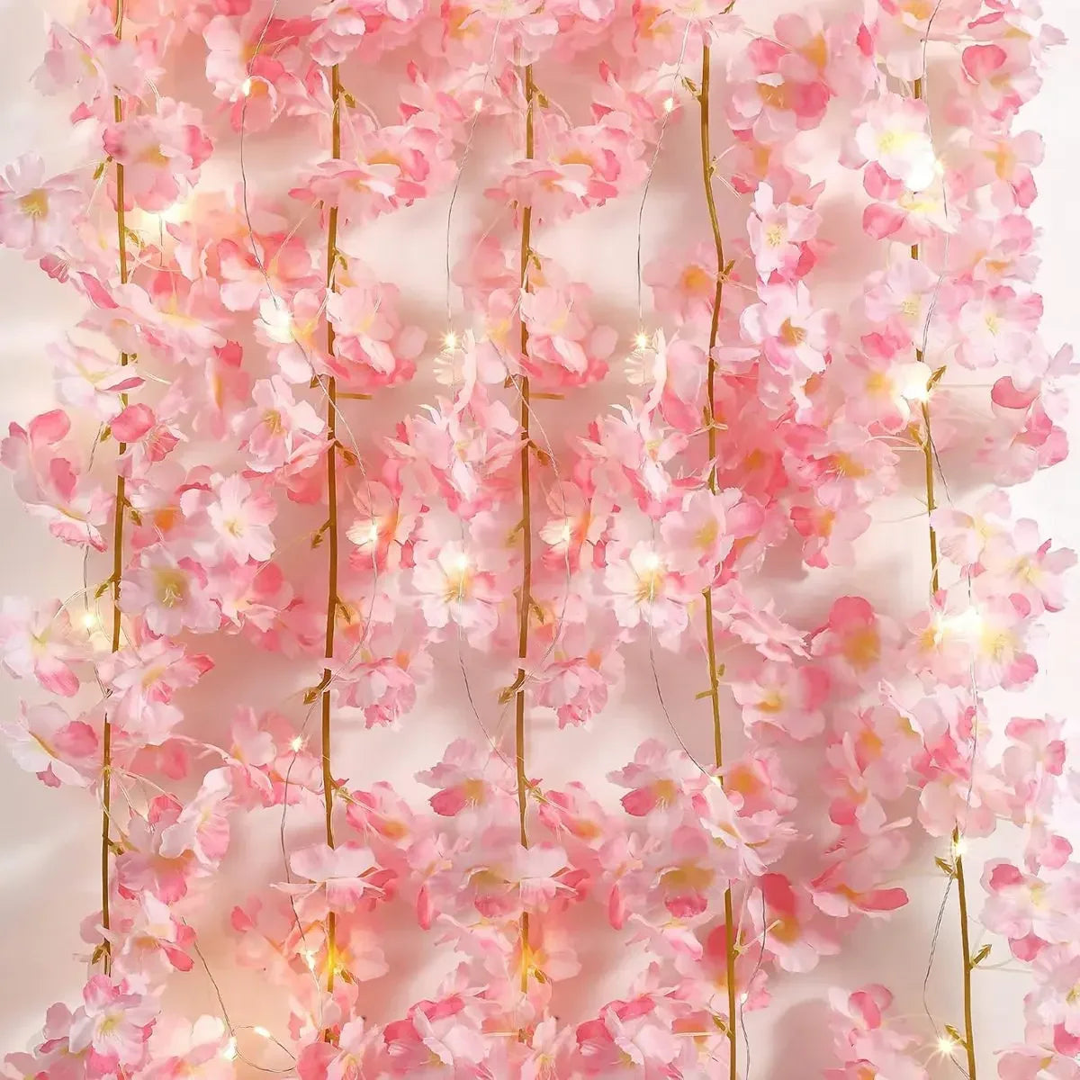 Pink cherry blossom string lights garland with glowing blossoms hanging vertically