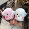 A pair of fluffy marshmallow plush toys in pink and light blue are held by a hand.