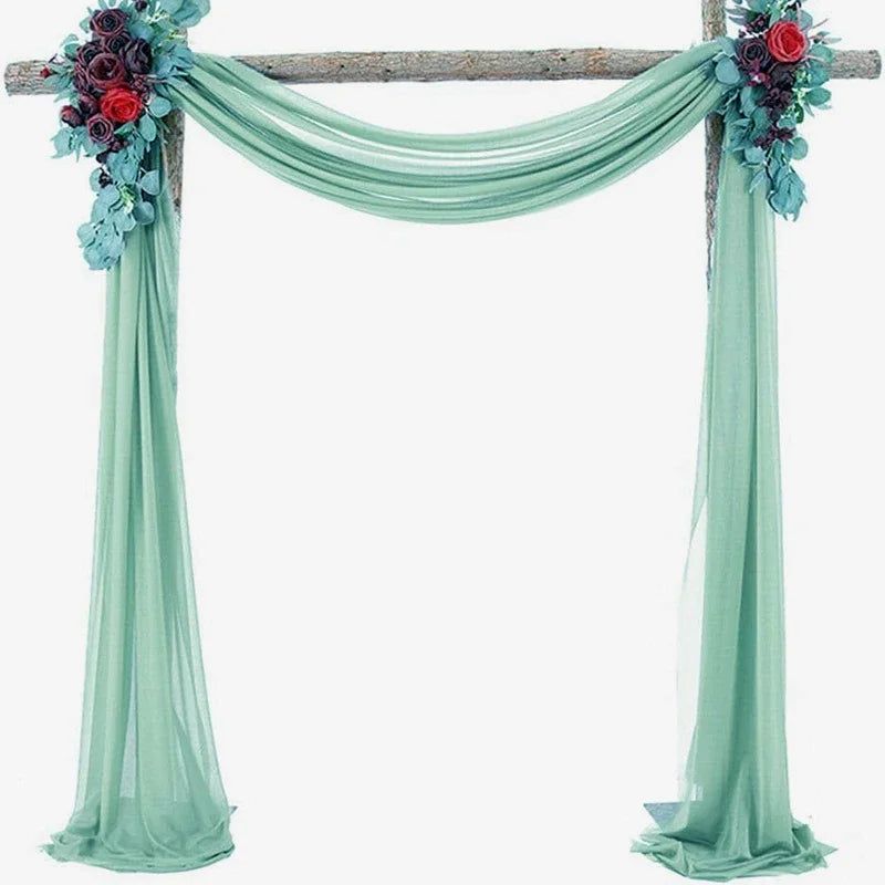 A wedding arch decorated with teal chiffon draping fabric panels and floral accents.